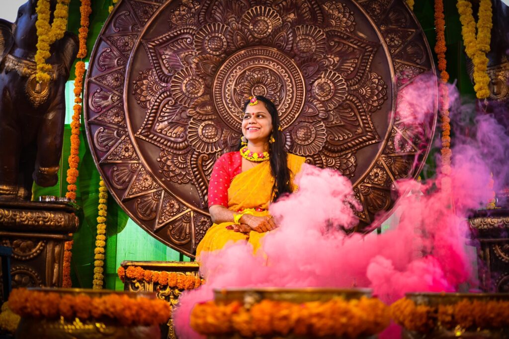 On the Ocassion of haldi A Telugu groom seated on the haldi chair with vibrant colours from a smoke bomb filling the scene, beautifully captured by Framesflow Photography in Hyderabad.