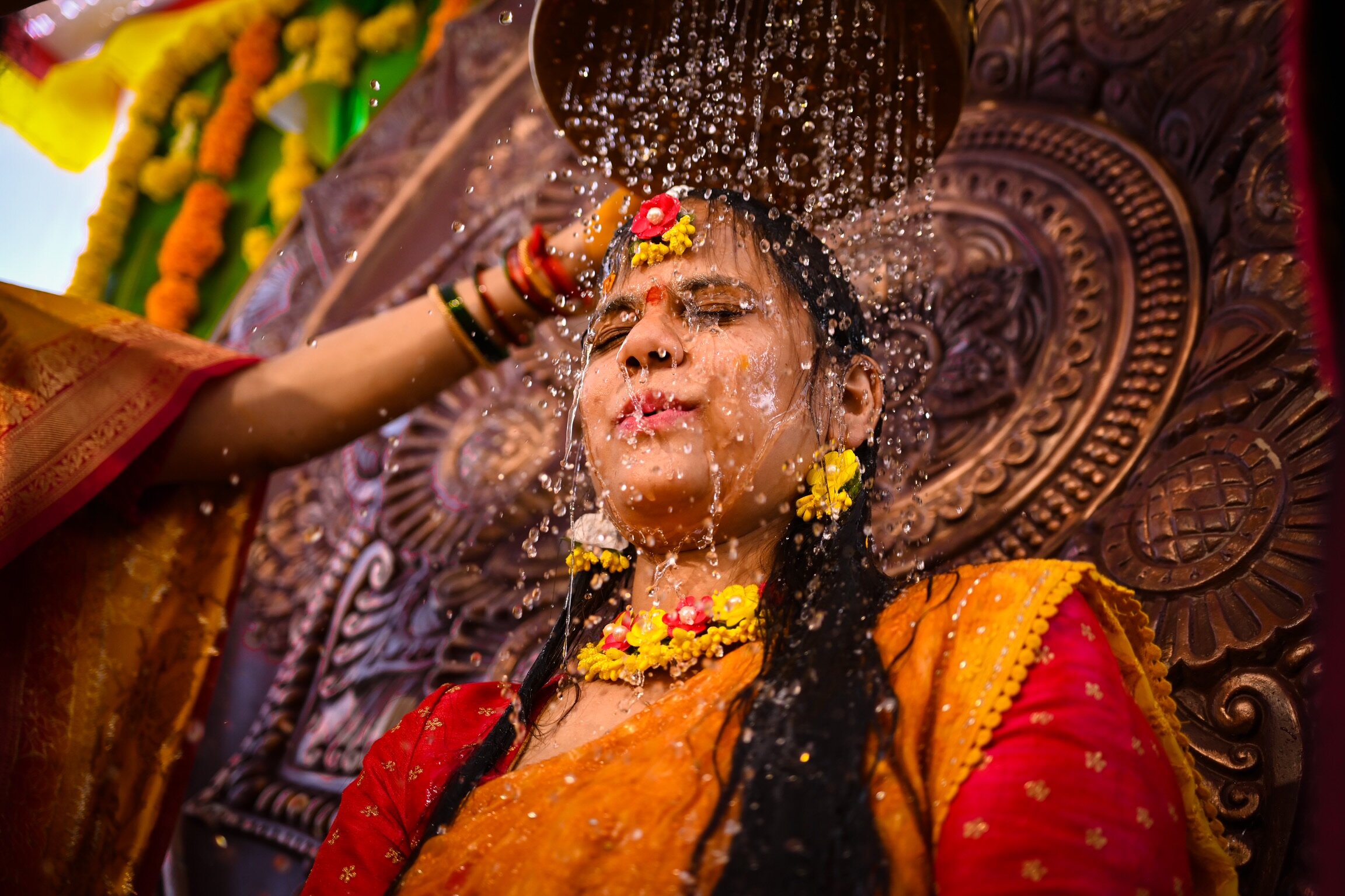 The Telugu bride feels her haldi occasion and her mother pours the water droplets beautifully captured by Framesflow photography in Hyderabad