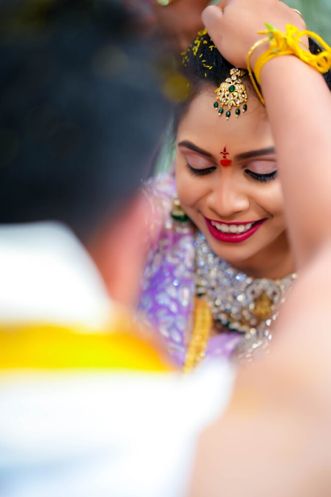 A beautiful Telugu bride feeling shy behind the groom during their wedding occasion, captures Framesflow photography in Hyderabad.