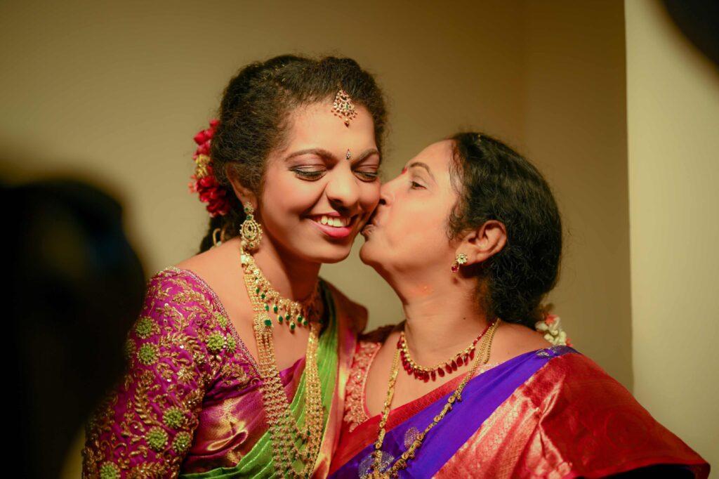 Telugu bride and her mother looks happily and kissed her daughters cheek on her wedding ceremony captures by Framesflow photography in Hyderabad.