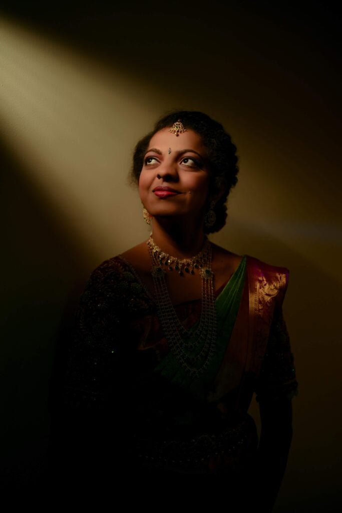 A beautiful Telugu bride standing still, illuminated by light rays, captured by Framesflow Photography in Hyderabad.