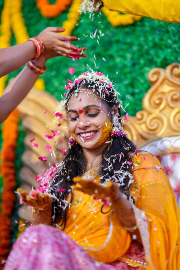 The Telugu bride pouring flowers by her friends during on haldi occasion with the mesmerising look captured by Framesflow photography in hyderabad